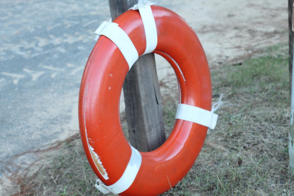 A life preserver hanging on a post by a beach.