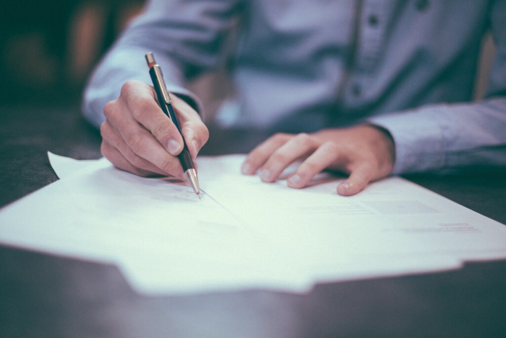 An individual holding a pen and signing documents.